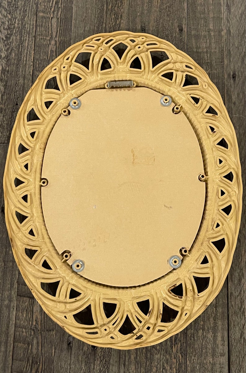 Puede incluir: Un espejo grande de forma ovalada con un marco decorativo y ornamentado. El marco est&aacute; hecho de un material beige claro y tiene un dise&ntilde;o delicado e intrincado. El espejo est&aacute; rodeado por un fino borde plateado.