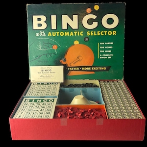 May include: Vintage Bingo game set in a red box. The box lid is green with the word "BINGO" and "with AUTOMATIC SELECTOR". Includes bingo cards, number markers, and a ball selector. A complete set for parties, homes, and clubs.