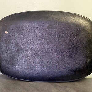 May include: Black oval serving tray with woven yellow handles. The tray has a textured surface and a dark color. The handles are made of a woven material. A small sticker is on the tray.