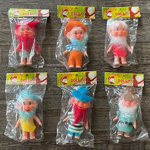 May include: Six small plastic dolls in individual packaging. Each doll has a different colored hat and facial features. The dolls are all wearing different colored clothing. The packaging is labeled "Nibleby Doll".