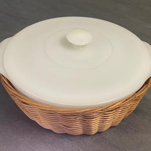 May include: White ceramic casserole dish with a lid and a woven wicker basket base.