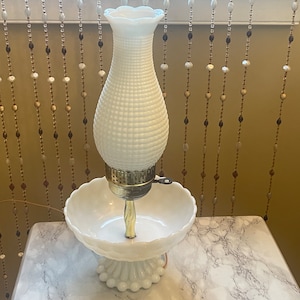 May include: White milk glass lamp with a textured bulb and a matching bowl base. The lamp has a gold metal base and a key to turn it on.