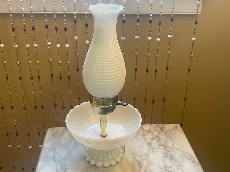 May include: White milk glass lamp with a textured bulb and a matching bowl base. The lamp has a gold metal base and a key to turn it on.