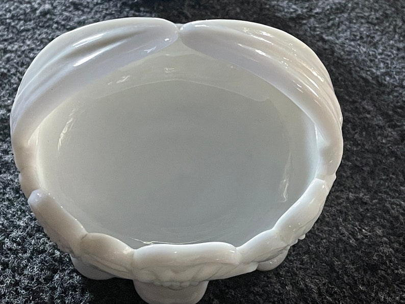 May include: White milk glass bowl with a scalloped edge and two handles. The bowl is empty and has a smooth, glossy finish.