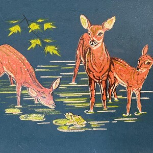 May include: A painting of three deer in a pond with a frog and lily pads. The deer are reddish-brown with white accents, and the water is a dark blue. Yellow leaves are in the upper left.