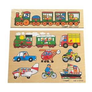 May include: A wooden puzzle set with a train, car, airplane, helicopter, motorcycle, truck, and boat. The puzzle pieces are colorful and have a cartoon style. The puzzle is made by Simplex and made in Holland.