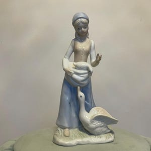 GIRL & DUCK FIGURINE…Girl with a Duck Inside Her Apron…Soft, Subtle Colors…Porcelain…Blue, Tan and White…Glazed…Vintage #W.T.1Bx