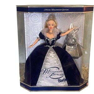 May include: A Barbie doll dressed in a blue and silver gown with a crown on her head. The doll is in a box with the words "Millennium Princess Barbie" on it. The box is labeled "Special Millennium Edition".
