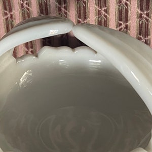 May include: White milk glass bowl with two handles. The bowl has a scalloped edge and a smooth, glossy finish.