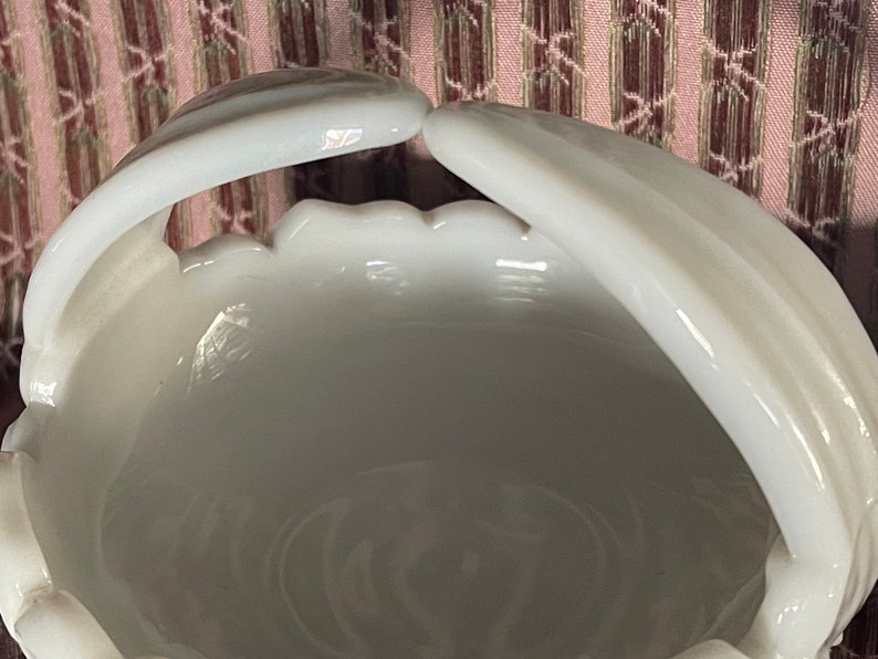 May include: White milk glass bowl with two handles. The bowl has a scalloped edge and a smooth, glossy finish.