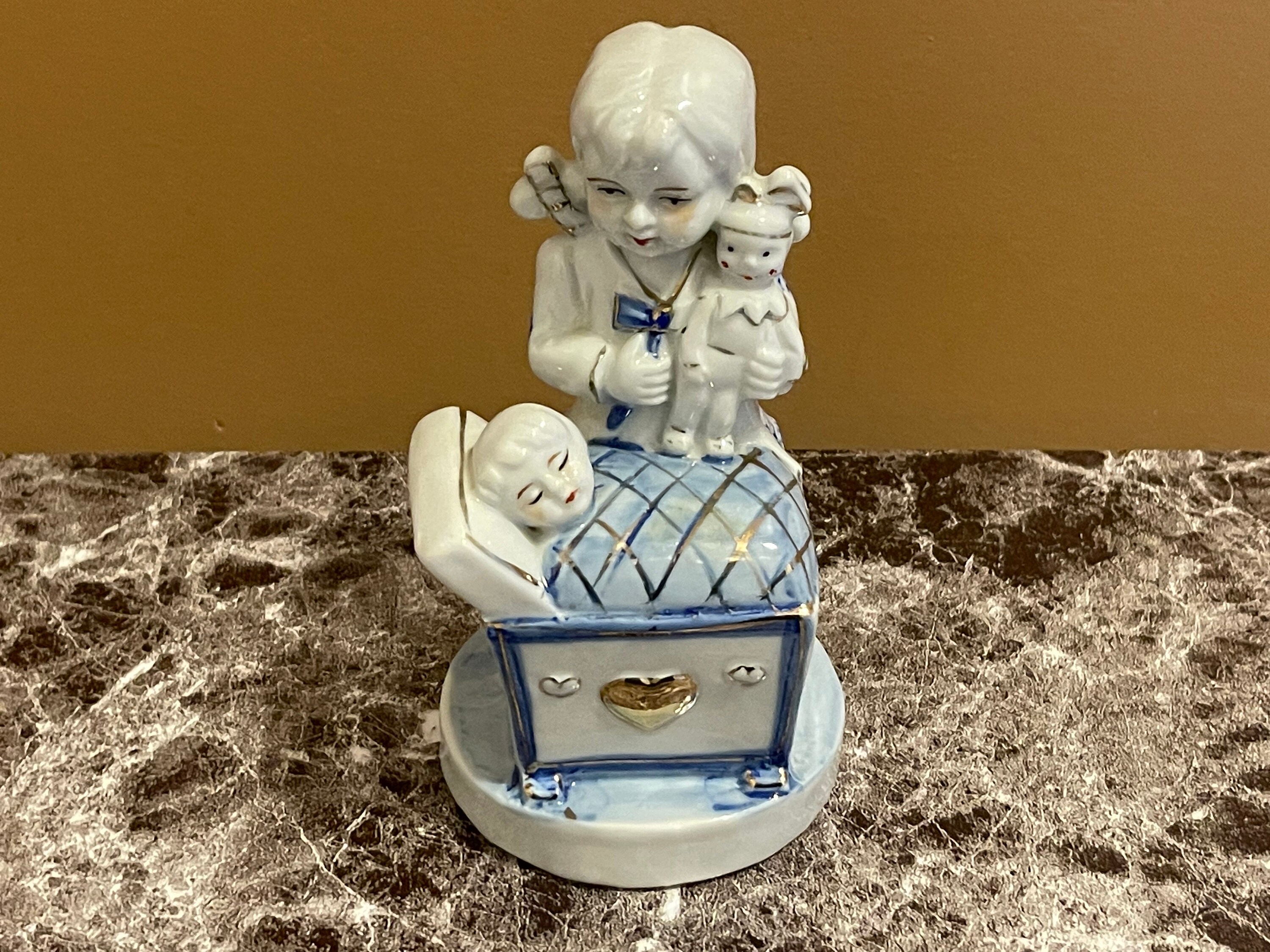 GIRL & CHILD FIGURINE…Girl With Doll Watching Sleeping Child…White Porcelain with Blue and Gold Accents…Center Heart…Glazed...Vintage #770