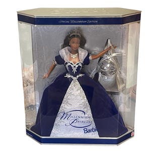 May include: A Barbie doll in a blue and silver gown with a crown. The doll is in a clear plastic box with a blue and silver background. The box says "Special Millennium Edition" and "Millennium Princess Barbie".