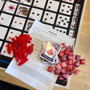 May include: A game board with red and pink chips, a deck of playing cards, and a set of instructions for the game "Sequence".