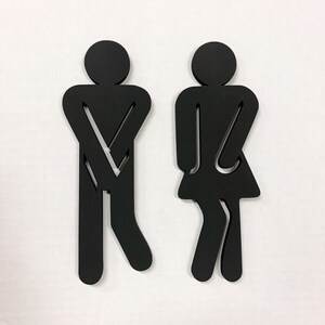 K&ouml;nnte beinhalten: Schwarze Silhouette einer Person mit verschr&auml;nkten Armen und eine schwarze Silhouette einer Person mit verschr&auml;nkten Armen und einem Rock. Die Silhouetten befinden sich auf einem wei&szlig;en Hintergrund.