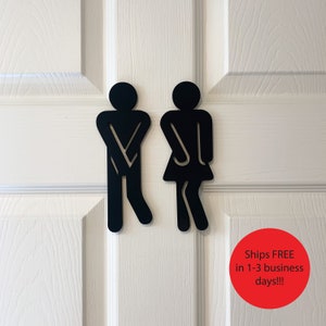 K&ouml;nnte beinhalten: Schwarze Silhouetten von Toilettenzeichen f&uuml;r M&auml;nner und Frauen an einer wei&szlig;en T&uuml;r. Das Schild lautet "Versand KOSTENLOS in 1-3 Werktagen!!!"