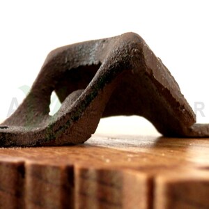 May include: A vintage metal bottle opener with a worn, rusty finish. The opener is mounted on a wooden base.
