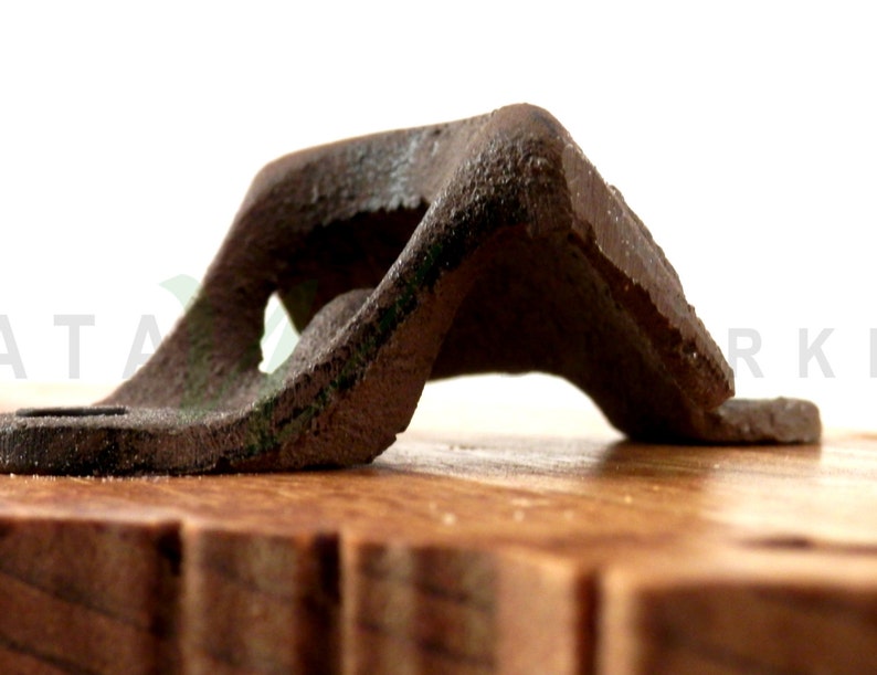 May include: A vintage metal bottle opener with a worn, rusty finish. The opener is mounted on a wooden base.
