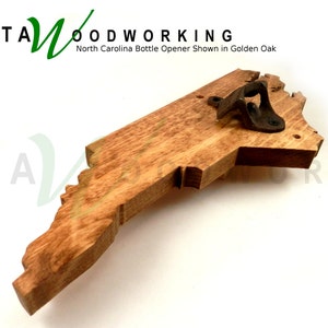 May include: A wooden bottle opener shaped like the state of North Carolina. The opener is made of golden oak wood and has a metal bottle opener attached to the top. The text "KATA WOODWORKING" is visible in the top left corner of the image. The text "North Carolina Bottle Opener Shown in Golden Oak" is visible below the logo.
