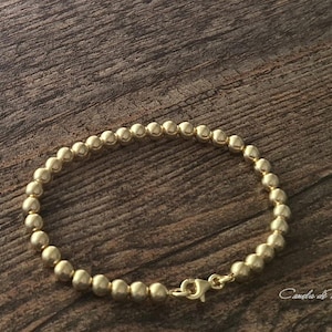 Armband mit 18-karätigen Goldperlen auf Sterlingsilber. Armband mit 18-karätig vergoldeten Perlen auf 925er Sterlingsilber. Stapelbares Armband.