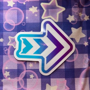 May include: A white arrow sticker with a blue and purple gradient. The arrow points to the right and has a chevron pattern.