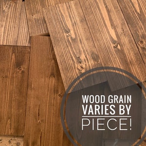 Op de afbeelding: Close-up van meerdere stukken hout met een donkerbruine vlek. De houtnerf varieert per stuk. De tekst "WOOD GRAIN VARIES BY PIECE!" is over de afbeelding gelegd.