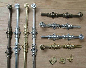 May include: A collection of decorative metal window sash locks and pulls in various finishes, including bronze, silver, and gold. The hardware features ornate detailing and includes matching screws and mounting plates. The items are arranged on a light wood surface.