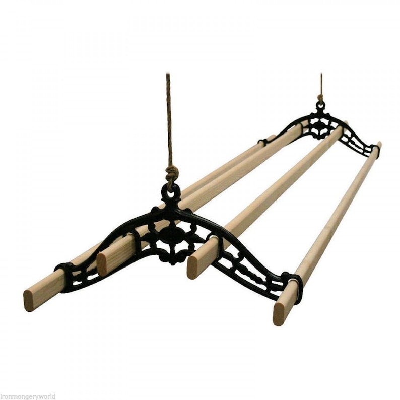 May include: A black cast iron ceiling-mounted clothes drying rack with three wooden dowels. The rack is suspended by a rope and features decorative scrollwork. The wooden dowels are approximately 36 inches long.