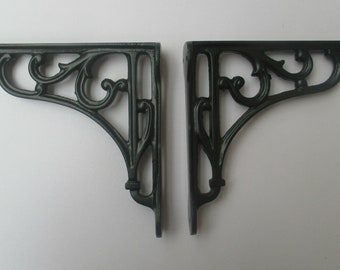 Puede incluir: Dos soportes de estante de hierro fundido negro con un diseño decorativo de desplazamiento.