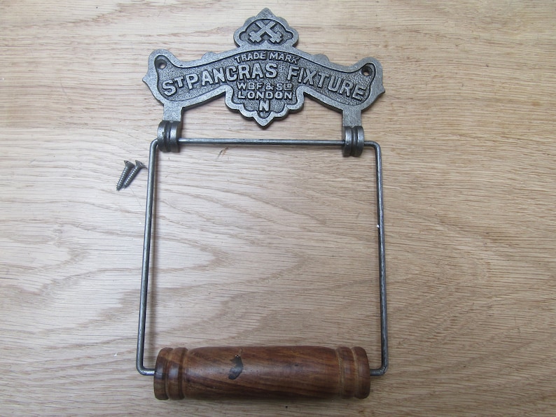 May include: Cast iron toilet paper holder with a wooden roller and a decorative metal sign that reads "TRADE MARK ST PANCRAS FIXTURE WBF & SO LONDON N".