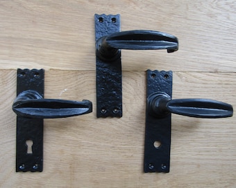 May include: Three black door handles with a decorative design. Each handle has a keyhole and a long, curved lever.