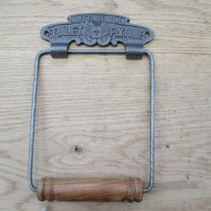 May include: A cast iron toilet paper holder with a wooden roller. The holder has a sign that reads "NOTTING HILL TOILET FIXTURES".