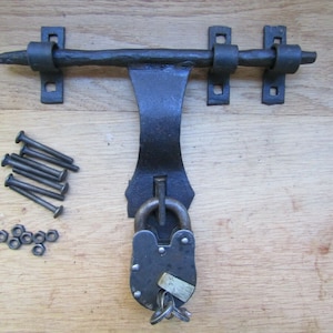 Puede incluir: Pestillo de puerta de metal negro con un candado y llaves. El pestillo tiene dos placas de montaje y viene con tornillos y tuercas.