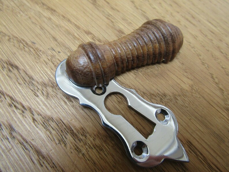 May include: A polished chrome door knob with a wooden handle. The handle is a dark brown color and has a ribbed texture. The knob is designed for a single door.