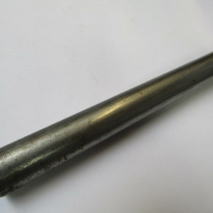 Puede incluir: Primer plano de una varilla de metal plateado. La varilla es lisa y tiene una superficie ligeramente texturizada.