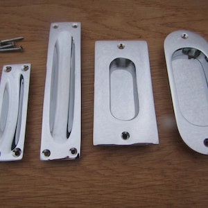 Può includere: Quattro maniglie per porte cromate con forma rettangolare e una maniglia ovale incassata. Le maniglie hanno due piccoli fori per le viti di montaggio.