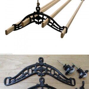 May include: A black cast iron clothes drying rack with wooden dowels, suspended by a rope. The rack is shown with its components, including decorative brackets, pulleys, rope, and mounting hardware. A vintage-style laundry solution.