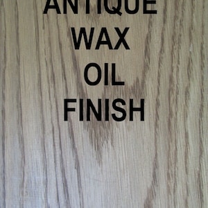 May include: Close-up of a wood surface with a light brown stain. The surface has a grainy texture. The text "Antique Wax Oil Finish" is printed in black on the wood.