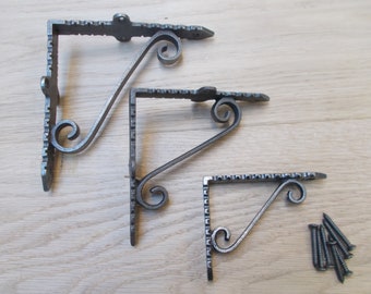 Puede incluir: Tres escuadras decorativas de hierro forjado con un acabado gris oscuro envejecido. Cada escuadra presenta un diseño en espiral y un borde superior decorativo. Se incluye un pequeño montón de tornillos.