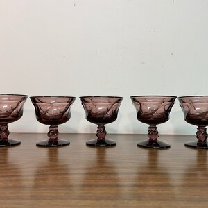 May include: Set of five purple glass stemmed dessert cups. The cups have a textured, swirling design.