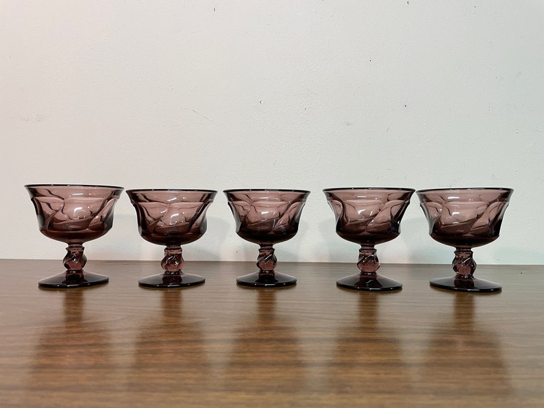 May include: Set of five purple glass stemmed dessert cups. The cups have a textured, swirling design.