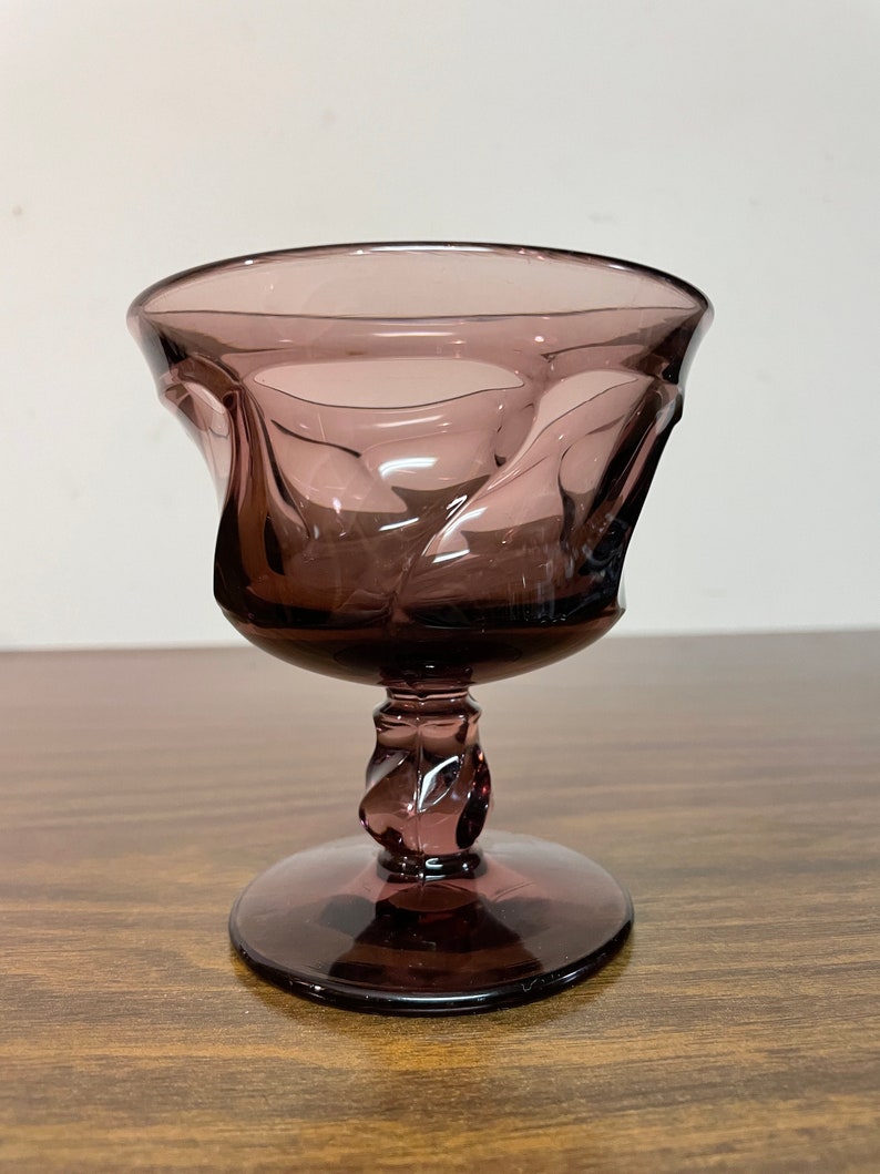 May include: A purple glass goblet with a twisted stem and a wide, flared bowl.