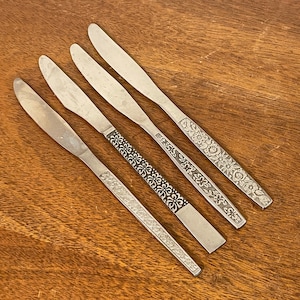 May include: Four silver dinner knives with floral designs on the handles.