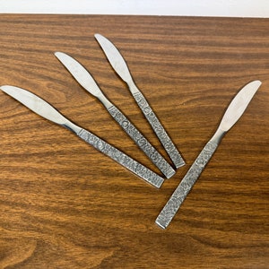 May include: Five silver dinner knives with an ornate floral design on the handles.