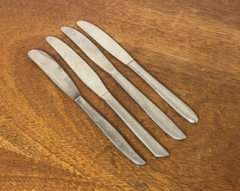 May include: Four silver butter knives with a starburst pattern on the blade.