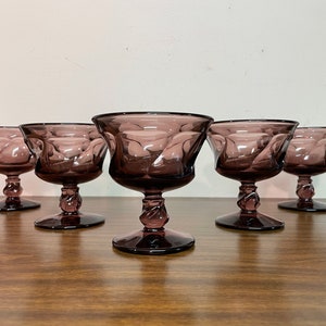 May include: Set of six purple glass dessert cups with a swirl design. The cups have a stemmed base and are perfect for serving ice cream, pudding, or other desserts.
