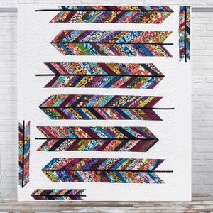 May include: A white quilt with a pattern of colorful arrows made from fabric scraps. The arrows are arranged in a vertical line down the center of the quilt. The fabric scraps are in a variety of colors, including purple, blue, green, and brown.