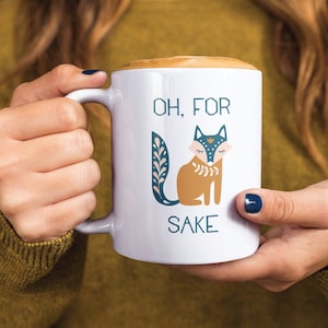May include: White ceramic mug with a brown fox illustration and the text "Oh, for sake".