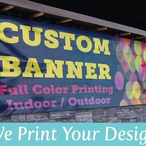 May include: A blue banner with the text "CUSTOM BANNER" in yellow letters and "Full Color Printing Indoor/Outdoor" in pink and white letters. The banner has a colorful background of overlapping circles. The text "We Print Your Design" is in white letters on a light blue background.
