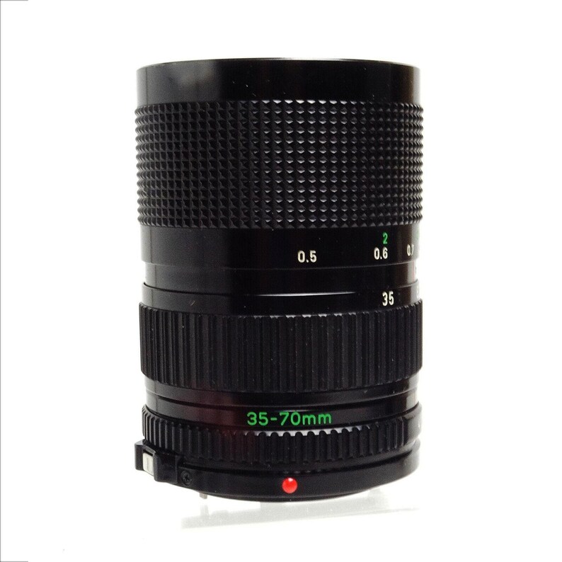 May include: A black Canon 35-70mm zoom lens with a silver ring and a red dot on the bottom.