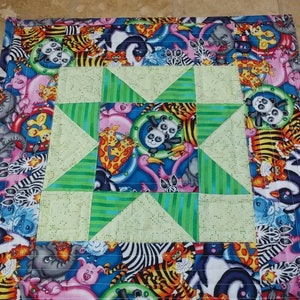 May include: A green, white, and blue patchwork quilt with a star design in the center. The quilt is made of fabric with various animal prints, including zebras, tigers, and pandas.